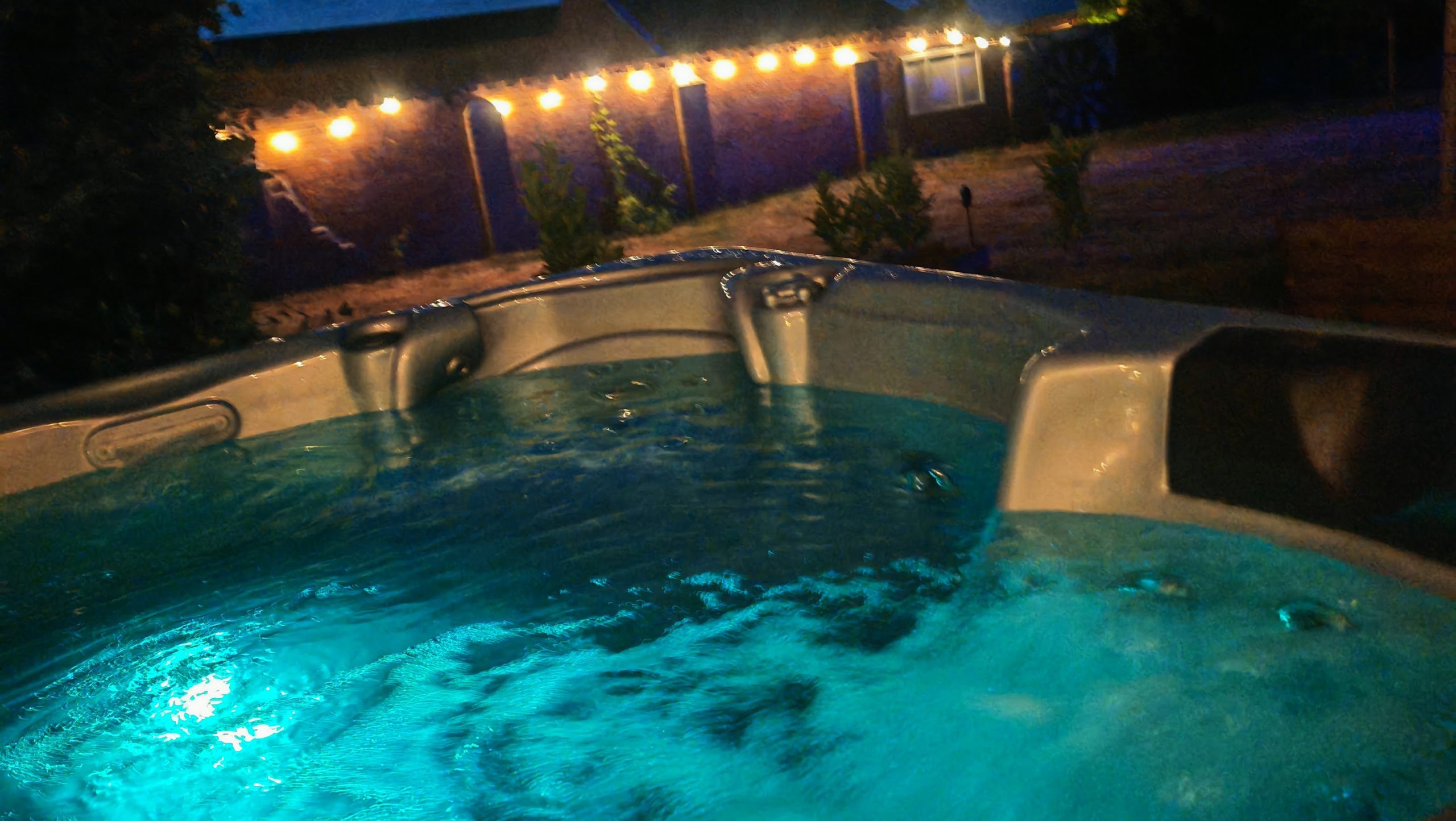 Steaming outdoor hot tub under festoon lights